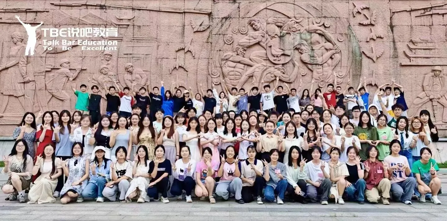 TBE students gathered for a group photo in front of a carved stone wall